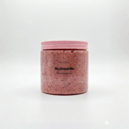 Donatella glow-boosting body scrub in a clear jar with a pink ribbed lid. The scrub is pink with visible exfoliating particles.